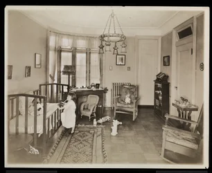 A girl holding a candle, climbing into a crib, in a bedroom of the A.C. Cronin residence